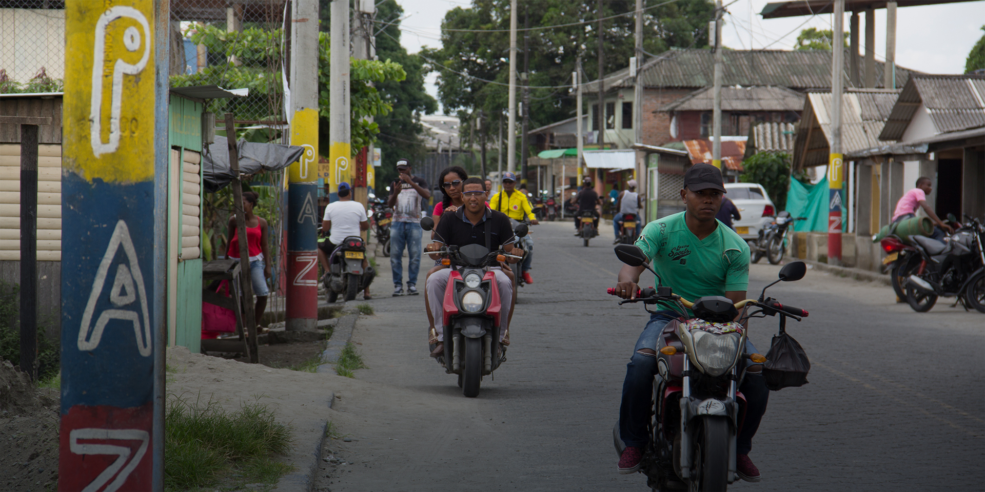 people on motorcycles in Colombia with the word paz or peace in spanish written on posts