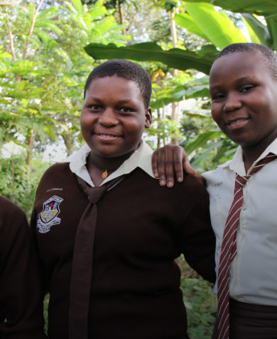 Three female students stand in their school's garden.