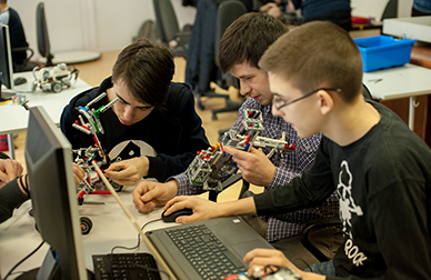 Three youths work on a robot.