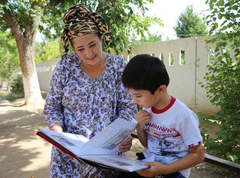 Manzura and her son Vohidjon read together.