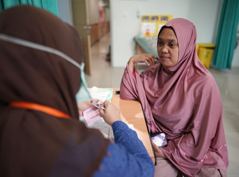 Woman talking to a community health worker in Indonesia