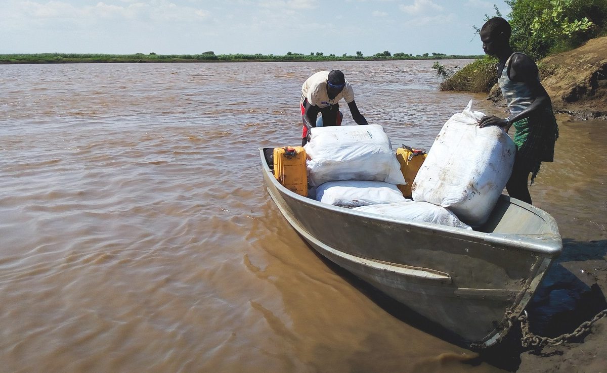 Men load a boat with bundles of mosquito nets