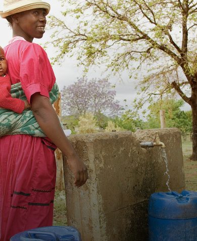 A woman and her child fill barrels with water in South Africa.