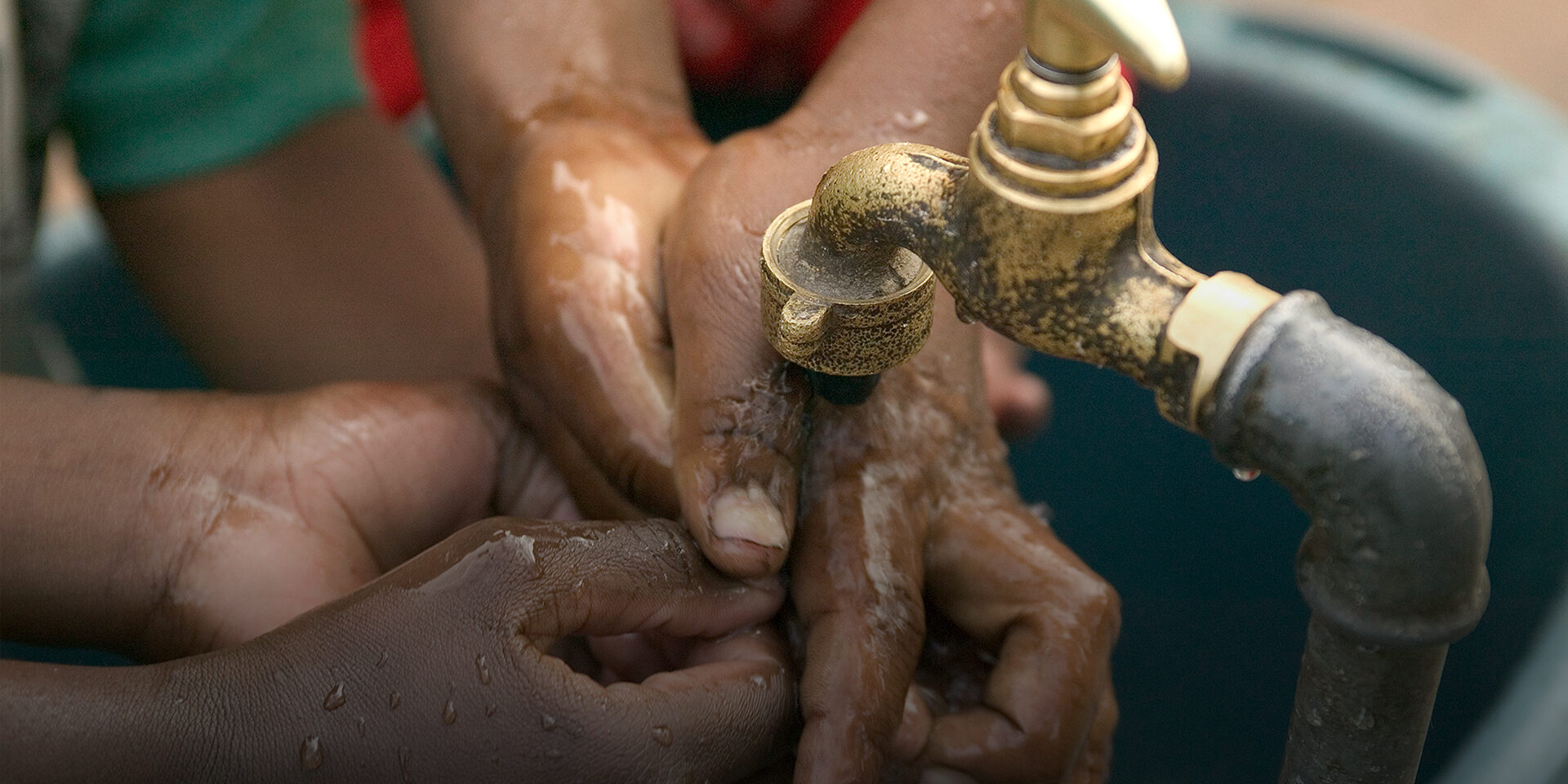 children watch hands under spigot.