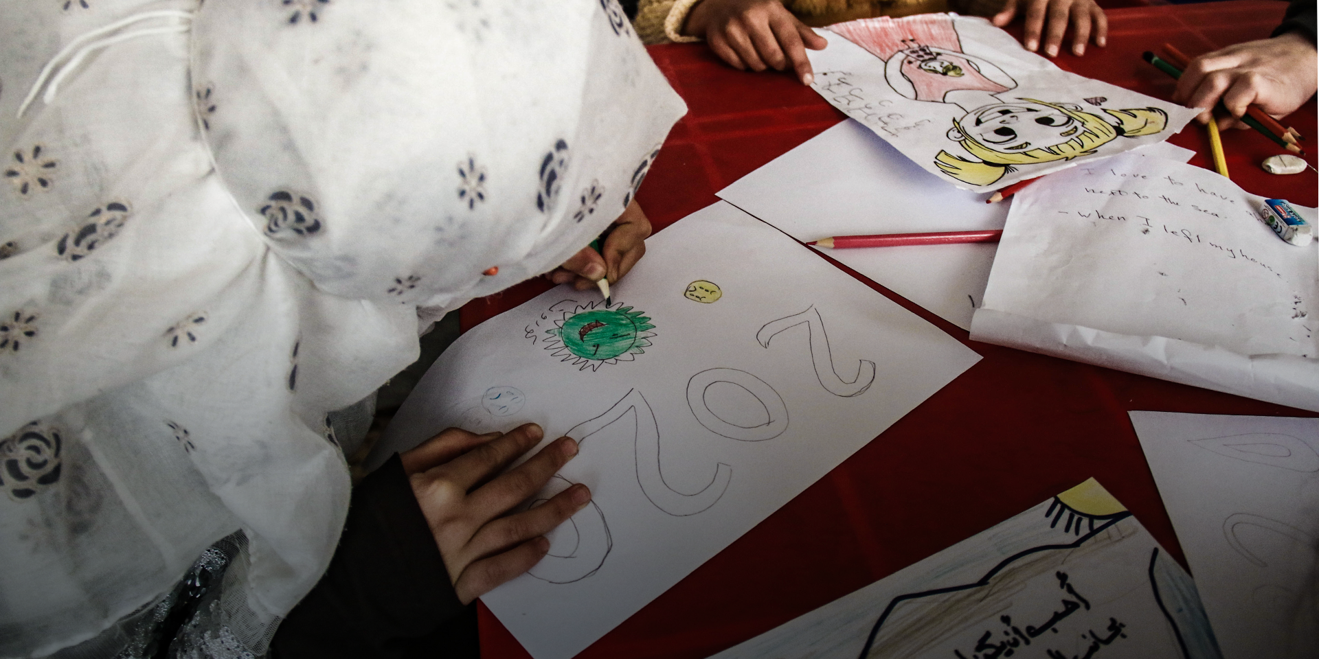 Syrian schoolgirls drawing pictures on their desks at school.