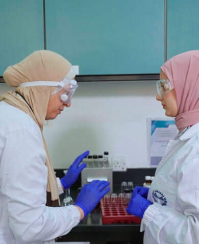 Two women in protective wear work in a lab