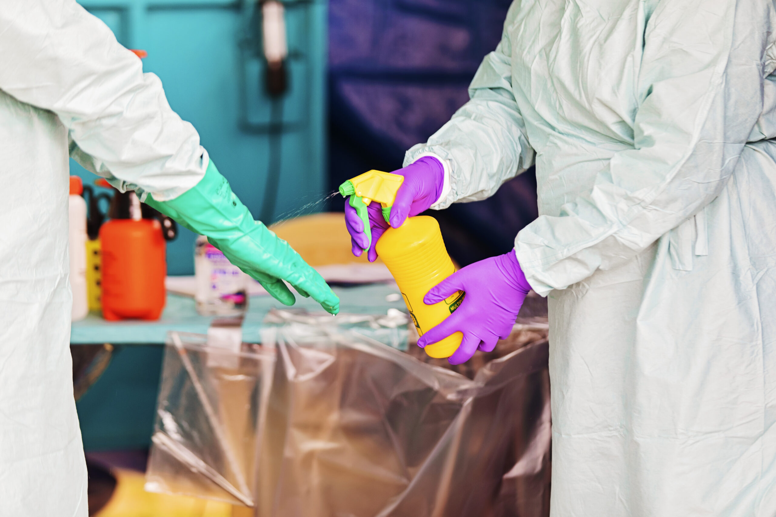one person spraying another's hands with gloves on