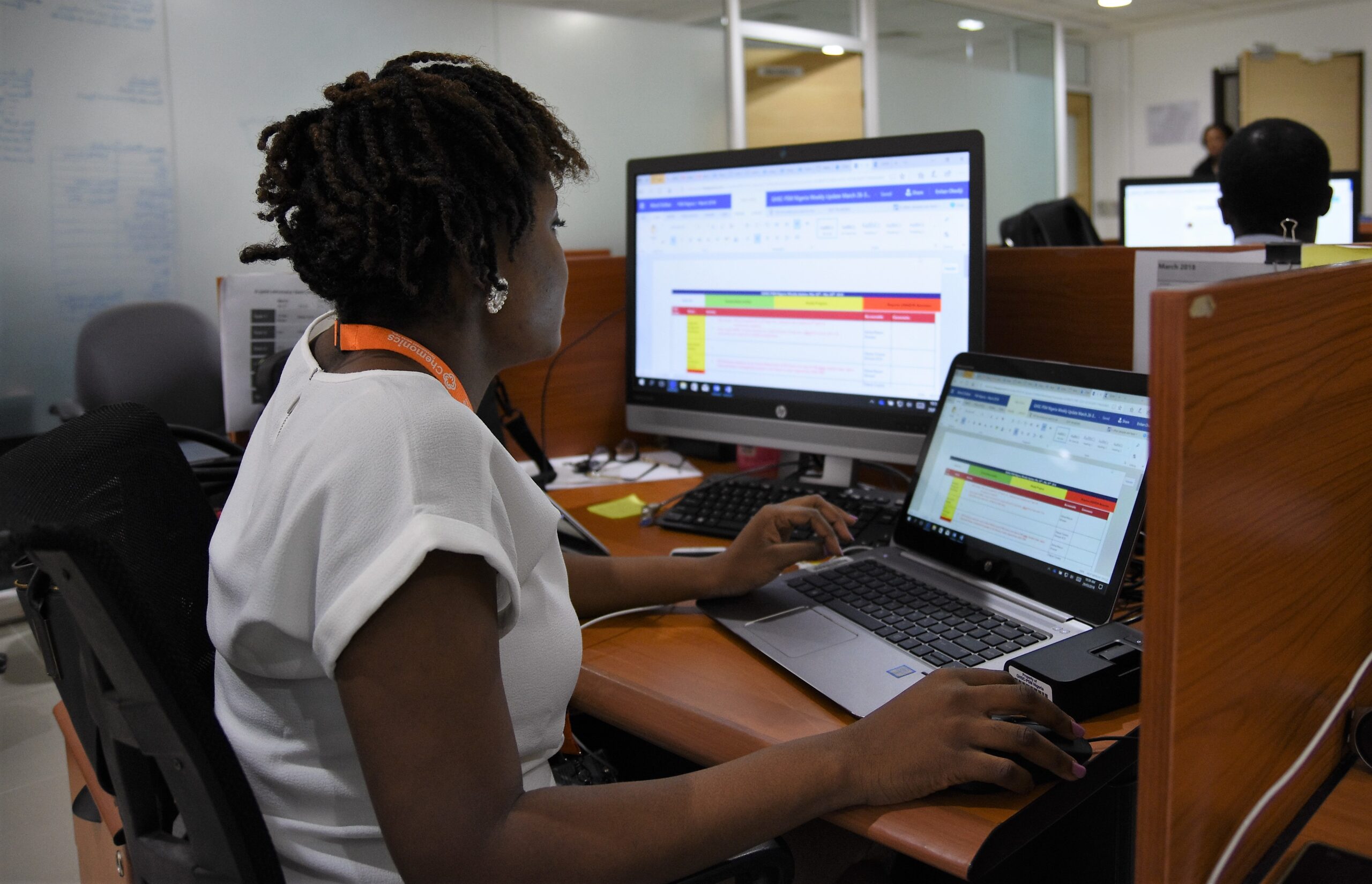 A woman looks at a tracker on two computer monitors