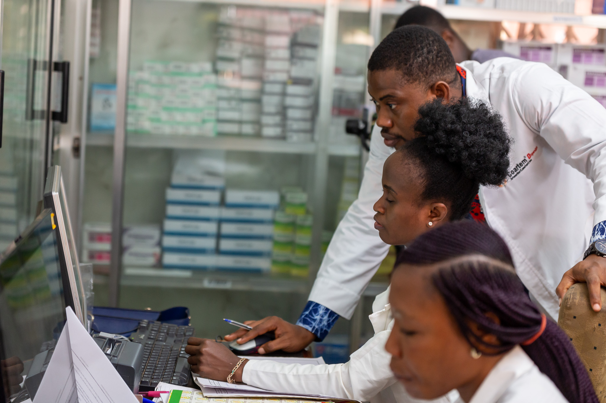 Three medical professionals in white coats look at a computer