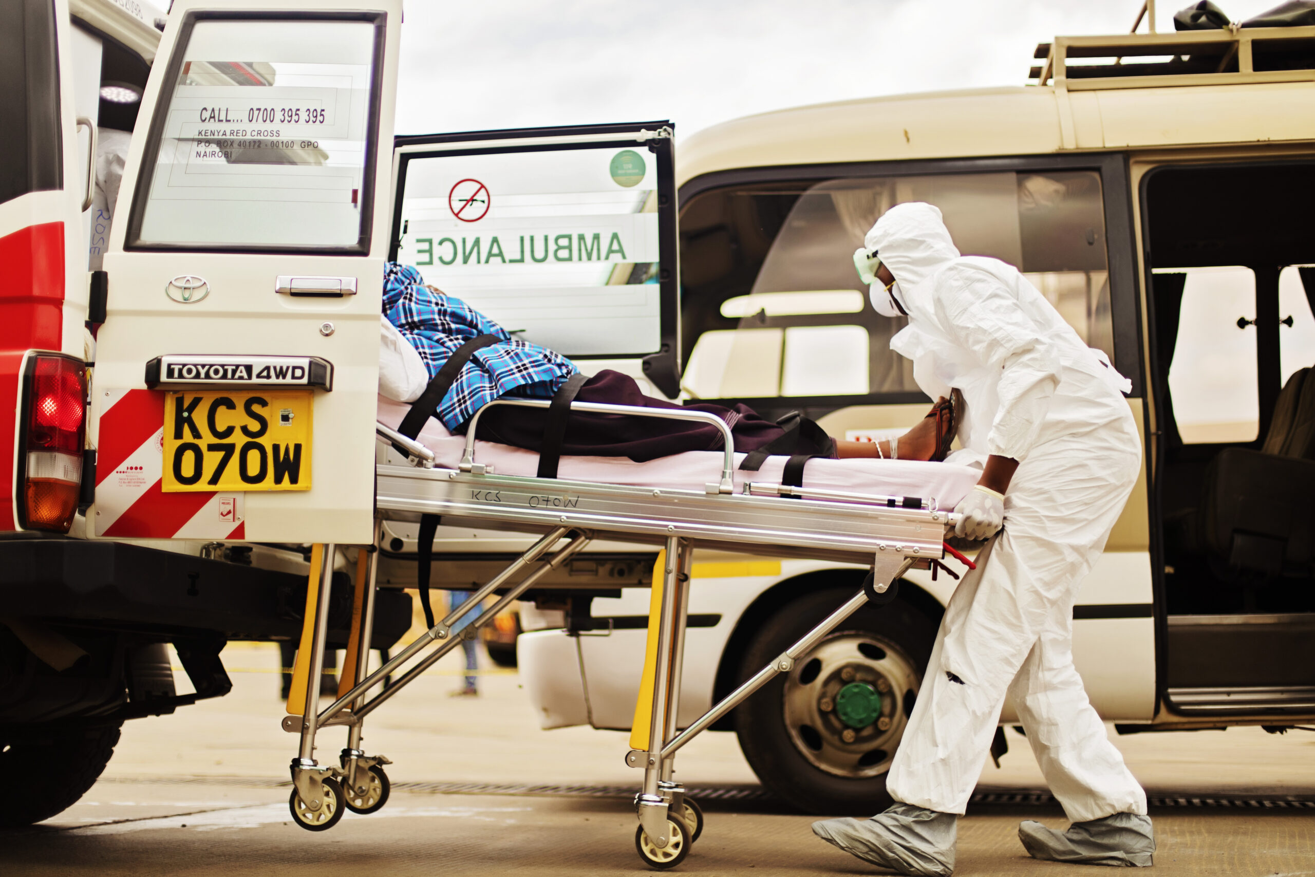 A health worker loads a patient into an ambulance